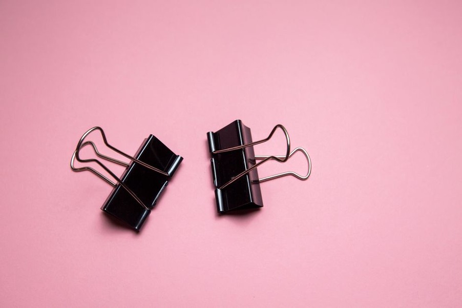Coral enamel barrette with black geometric lines against grey wool