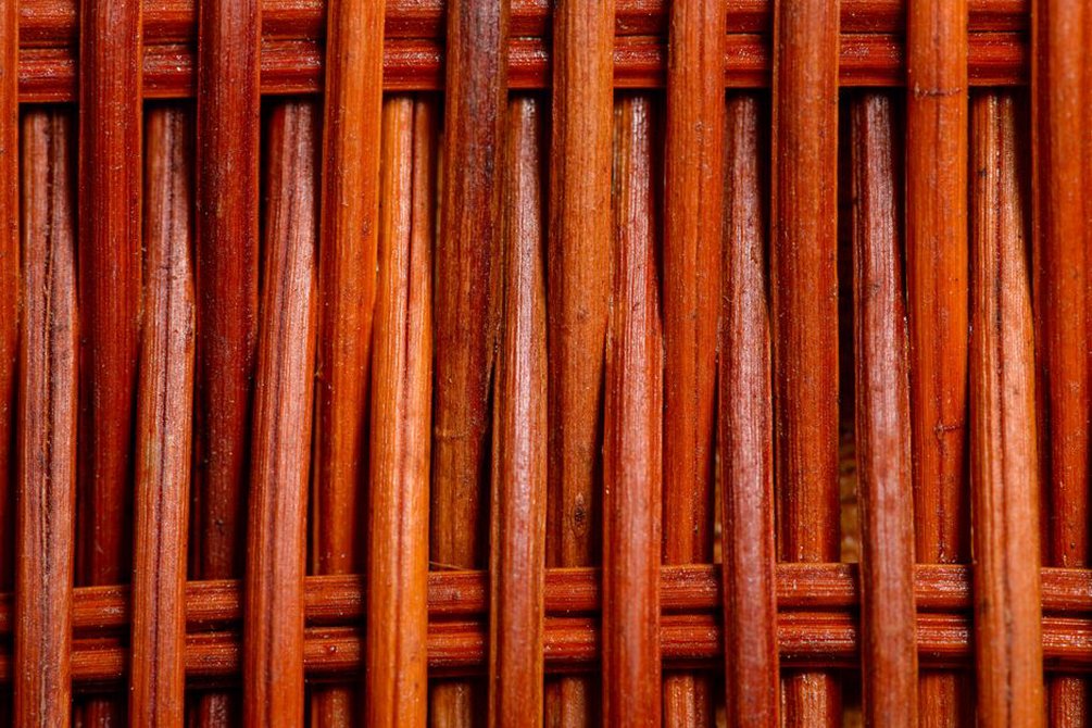 Close-up of natural reed weave and curved wooden handle on a vintage summer bag