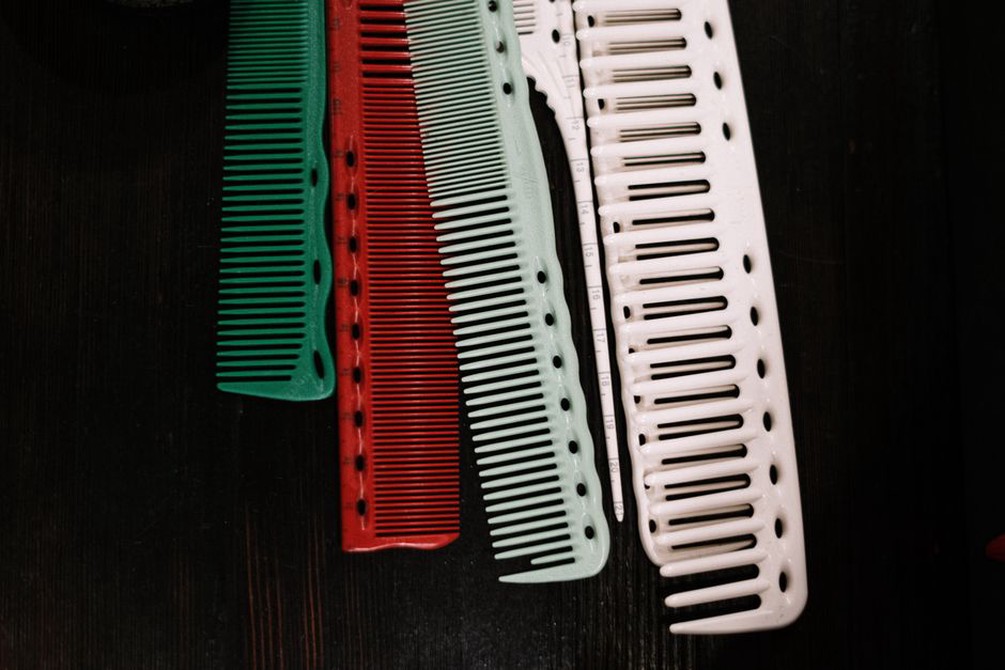 Assorted vintage hair combs and metal hairpins arranged on a polished wooden surface