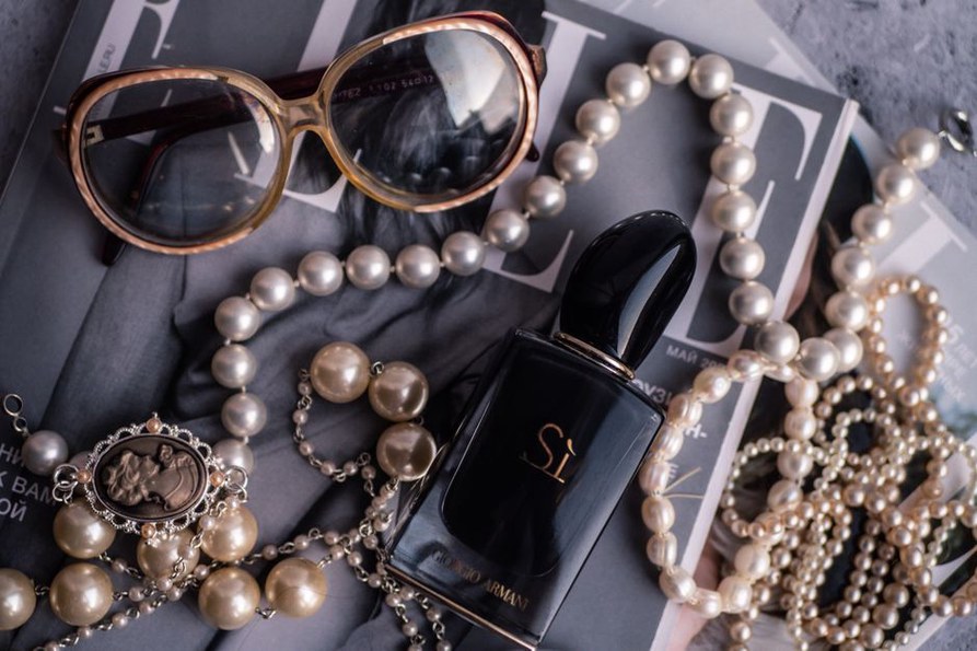 Close-up of a freshwater pearl chain draped over vintage cat-eye spectacles