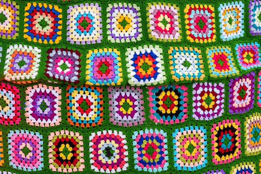 Vintage granny square scarf in mustard and avocado tones draped over a chair