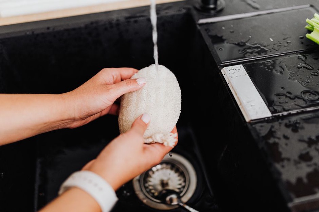 Woman gently washing a vintage crochet beanie in a ceramic basin