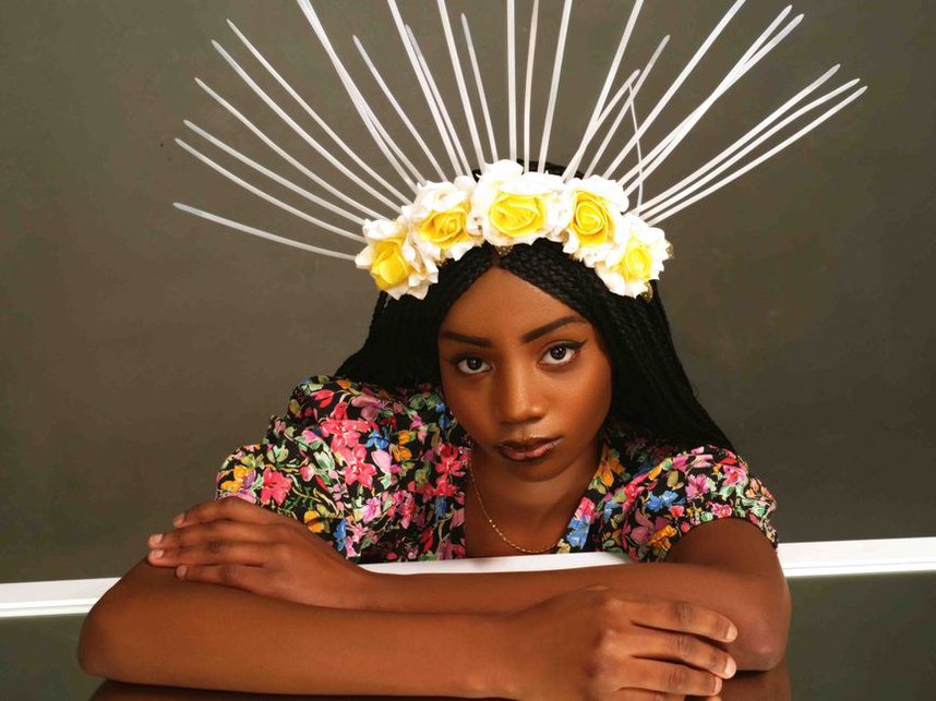 Ivory rose crown headband displayed on a velvet stand in soft daylight