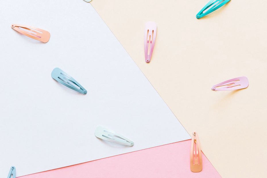Two pastel enamel Annabel clips, one light blue and one pink, laid flat on a linen cloth