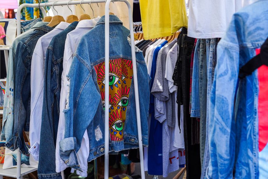 A row of vintage Summer of Love t‑shirts in rainbow colours at a UK flea market