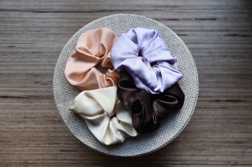 Silk scrunchie resting on natural linen fabric with a vintage comb nearby