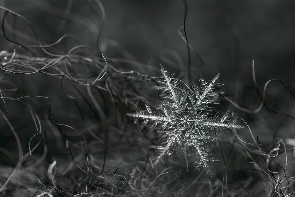 Close-up of hand-twisted silver wire with central crystal forming snowflake arms