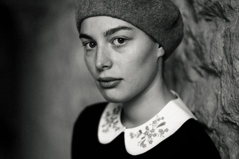 orange felt beret with embroidered white daisies displayed on a hat stand