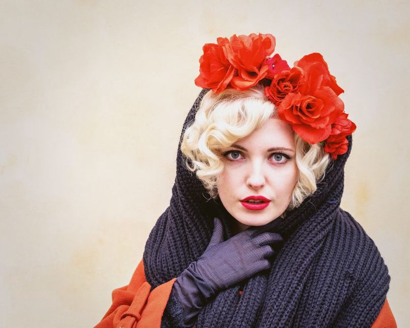 Handcrafted red rose crown headband on a display bust, showing velvety petals and wired construction