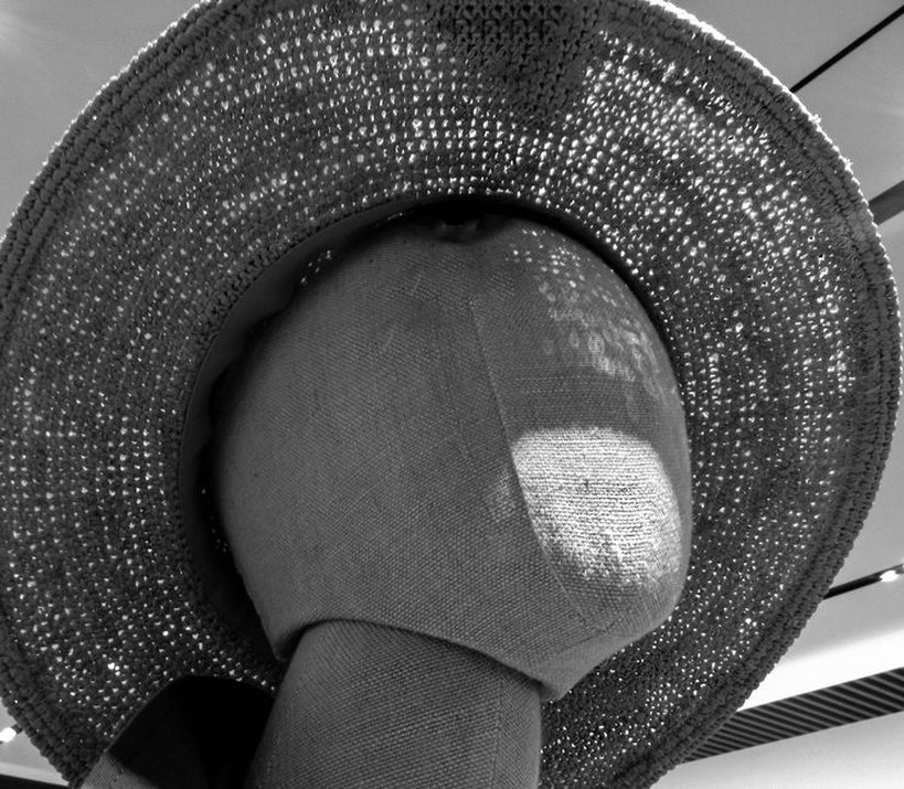 conical straw hat from the 1920s displayed on a felt mannequin, with a long hatpin inserted through the crown