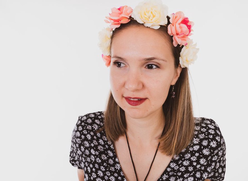Woman with a white blouse and jeans wearing an ivory rose crown headband in a sunlit room