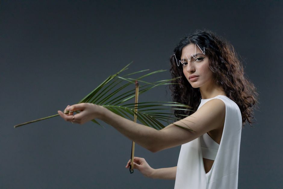 Woman in a modern outfit pinning a pink leaf barrette into her hair