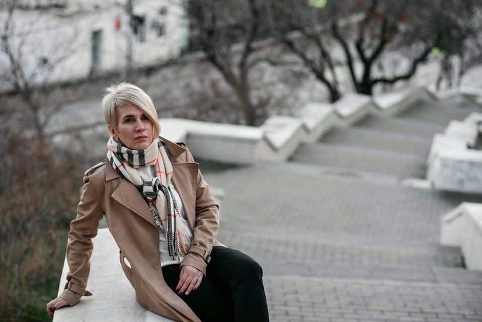 A granny square scarf styled over a beige trench coat for a vintage-modern look