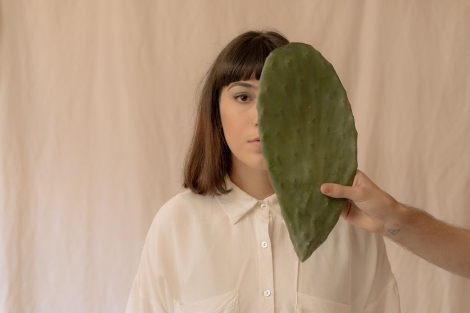 Sage green resin claw with cactus enamel worn in a half-up hairstyle
