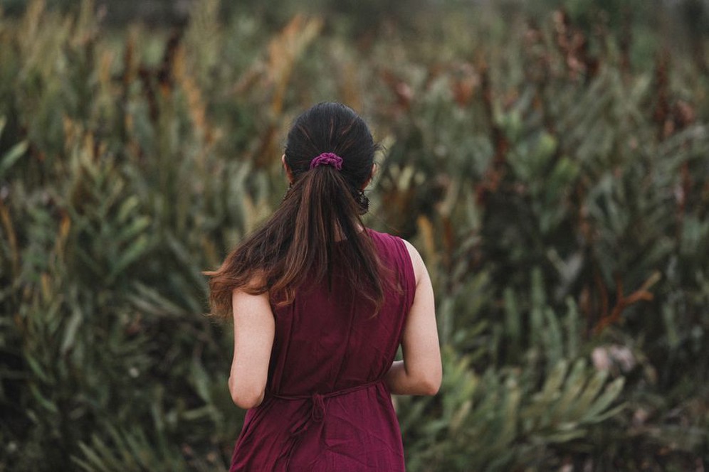 Low ponytail styled with deep aubergine scrunchie and cream silk blouse