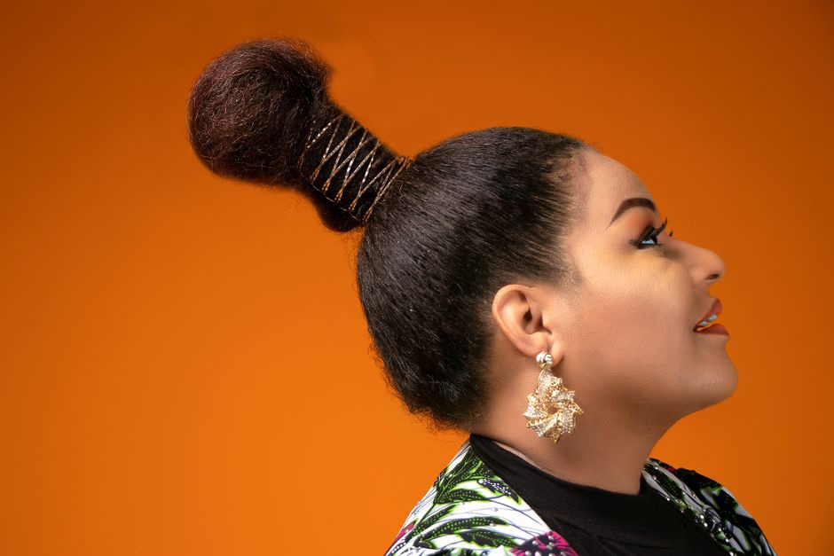 Coral sun burst earring cliped into a low side bun