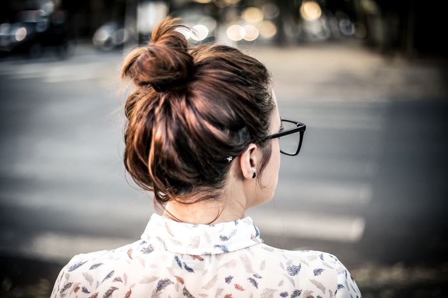 Low messy bun held by a tortoiseshell clip against a soft grey background