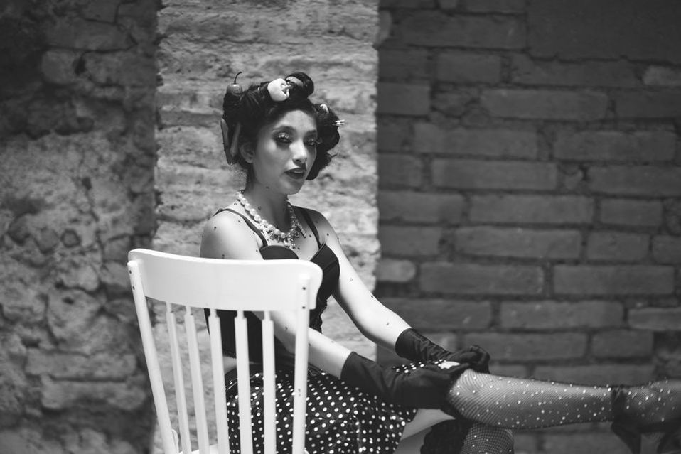 A small hat sits above carefully arranged curls