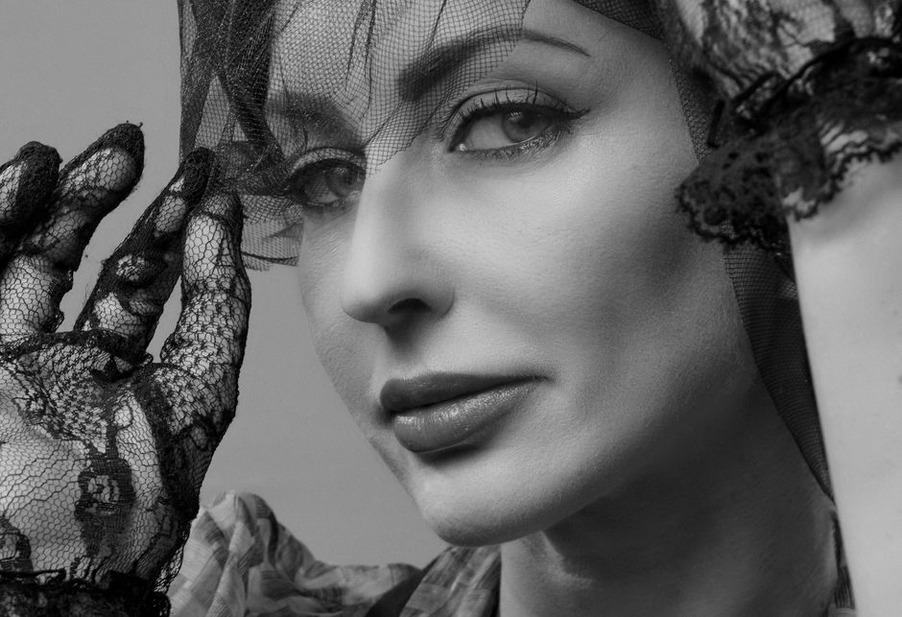 Floral lace falls from the brim of a dark hat